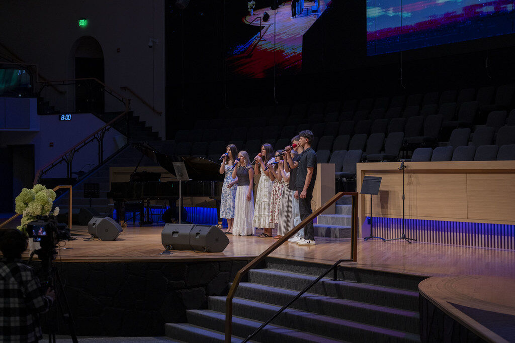Young singers with microphones on the dimly lit Sulamita Church stage during Friday youth